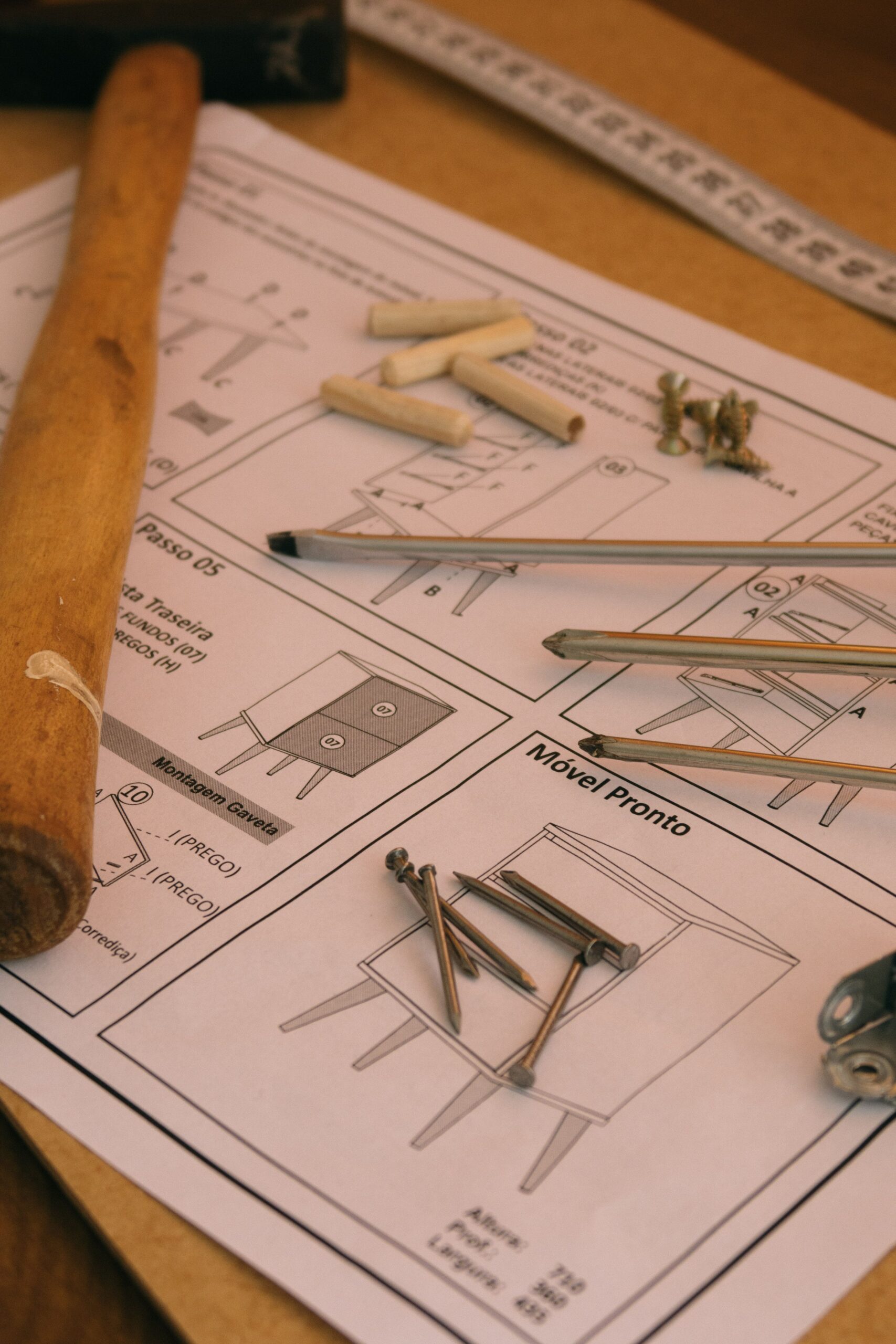 From above of scattered screwdrivers with dowel pins on paper instruction of how to assemble drawer cabinet